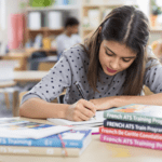 une fille assise à une table avec une pile de livres